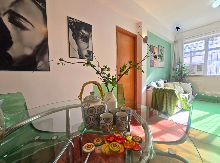 Glass dining table looking toward a green sofa and bright window